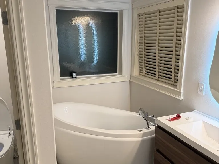 A corner soaking tub below plantation shutters