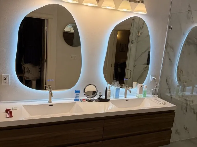 Two backlit oval mirrors above a floating timber vanity