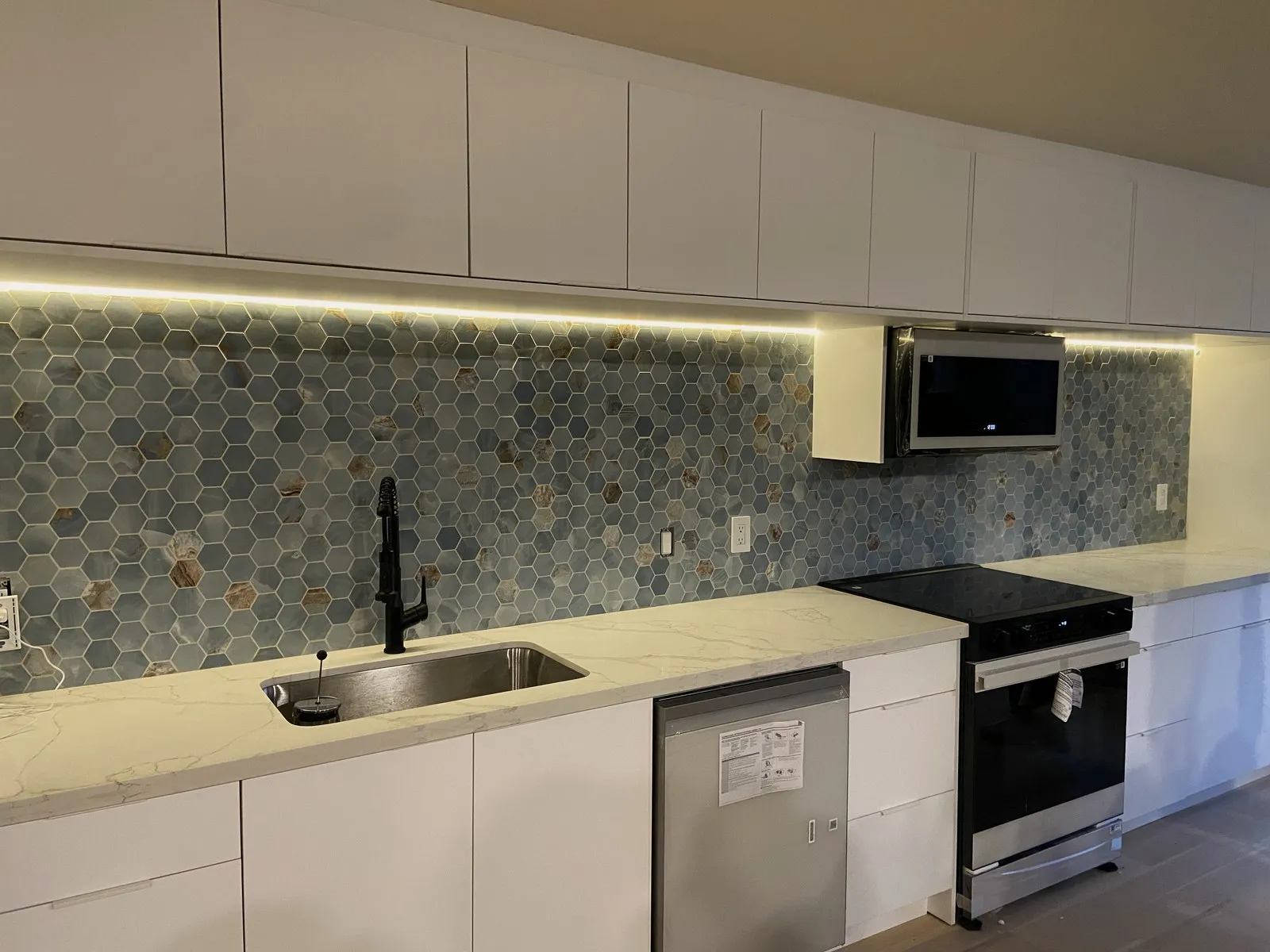 A remodeled kitchen with white cabinets and a tile backsplash