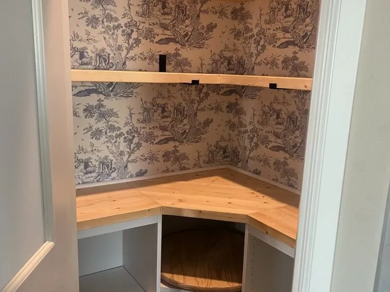 Timber pantry shelving against toile wallpaper