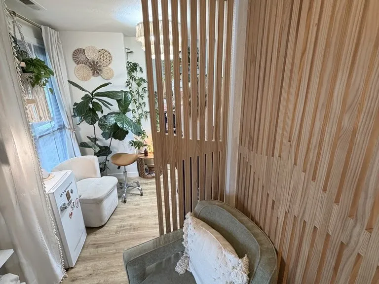 A slatted timber partition beside a round mirror and planting