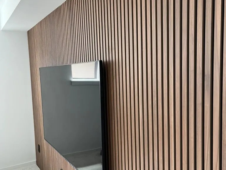 A slatted timber feature wall with a recessed television