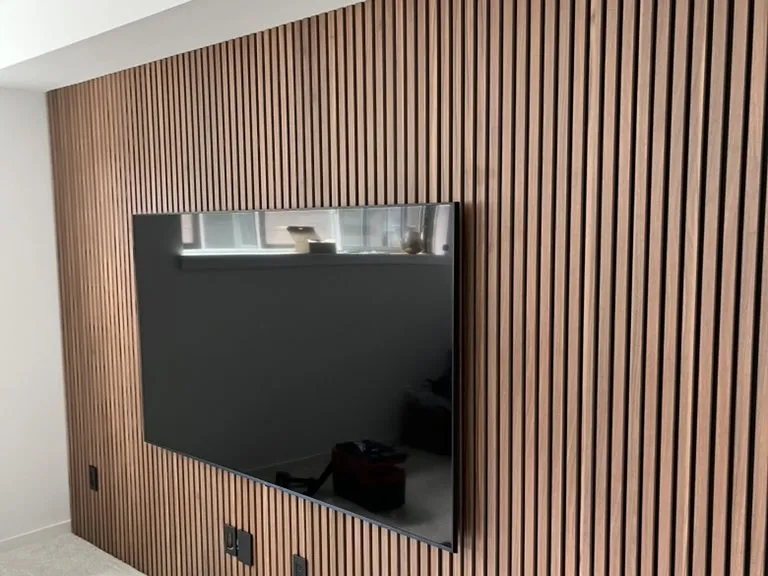 A slatted timber wall with a mounted television