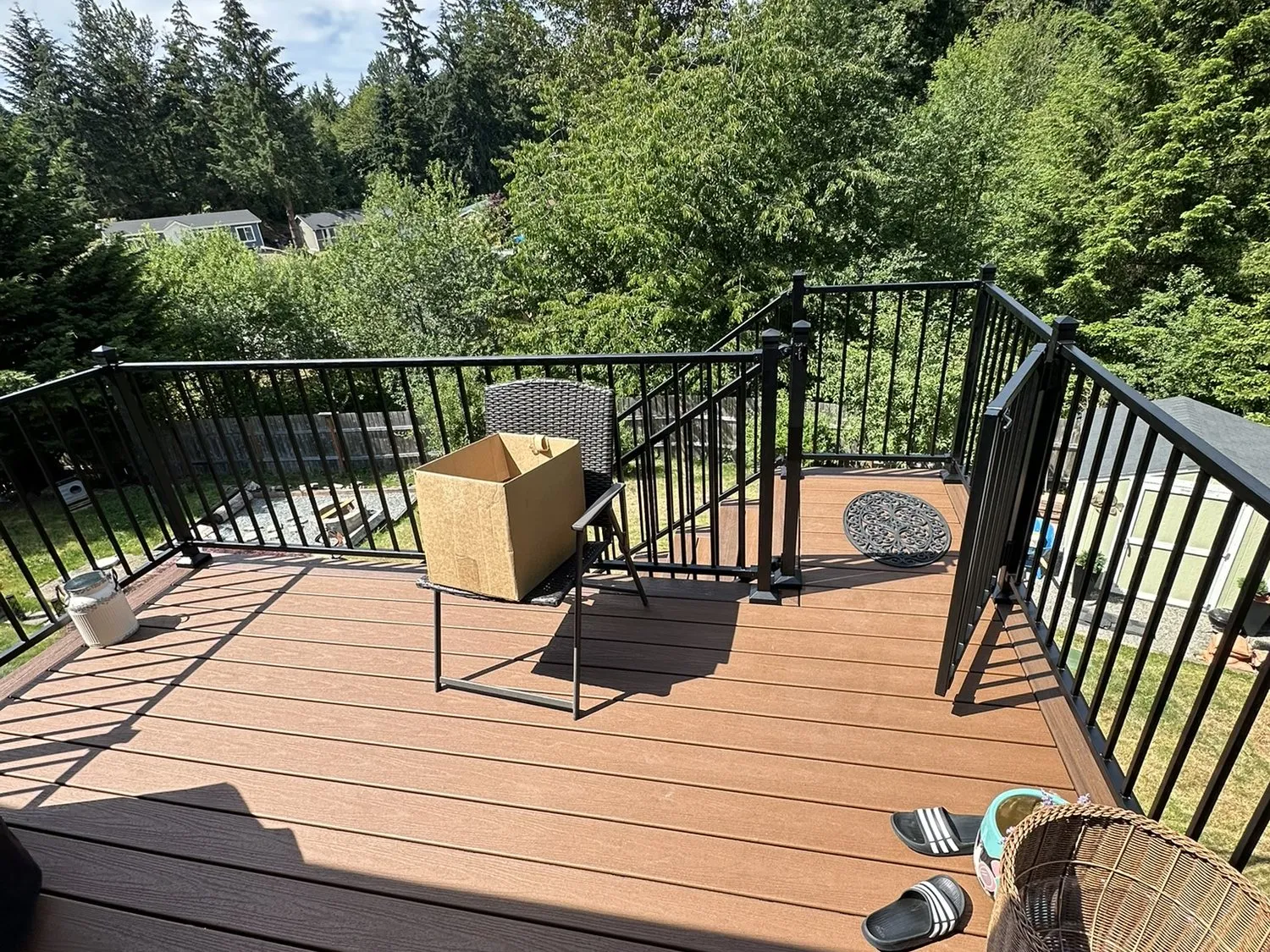 A composite deck with black metal railing, looking out to the trees