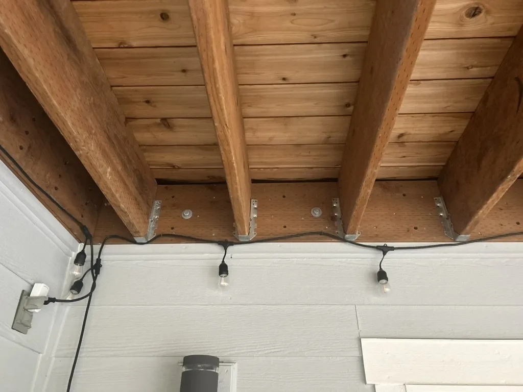 A cedar-clad ceiling under a covered deck, with lighting fitted