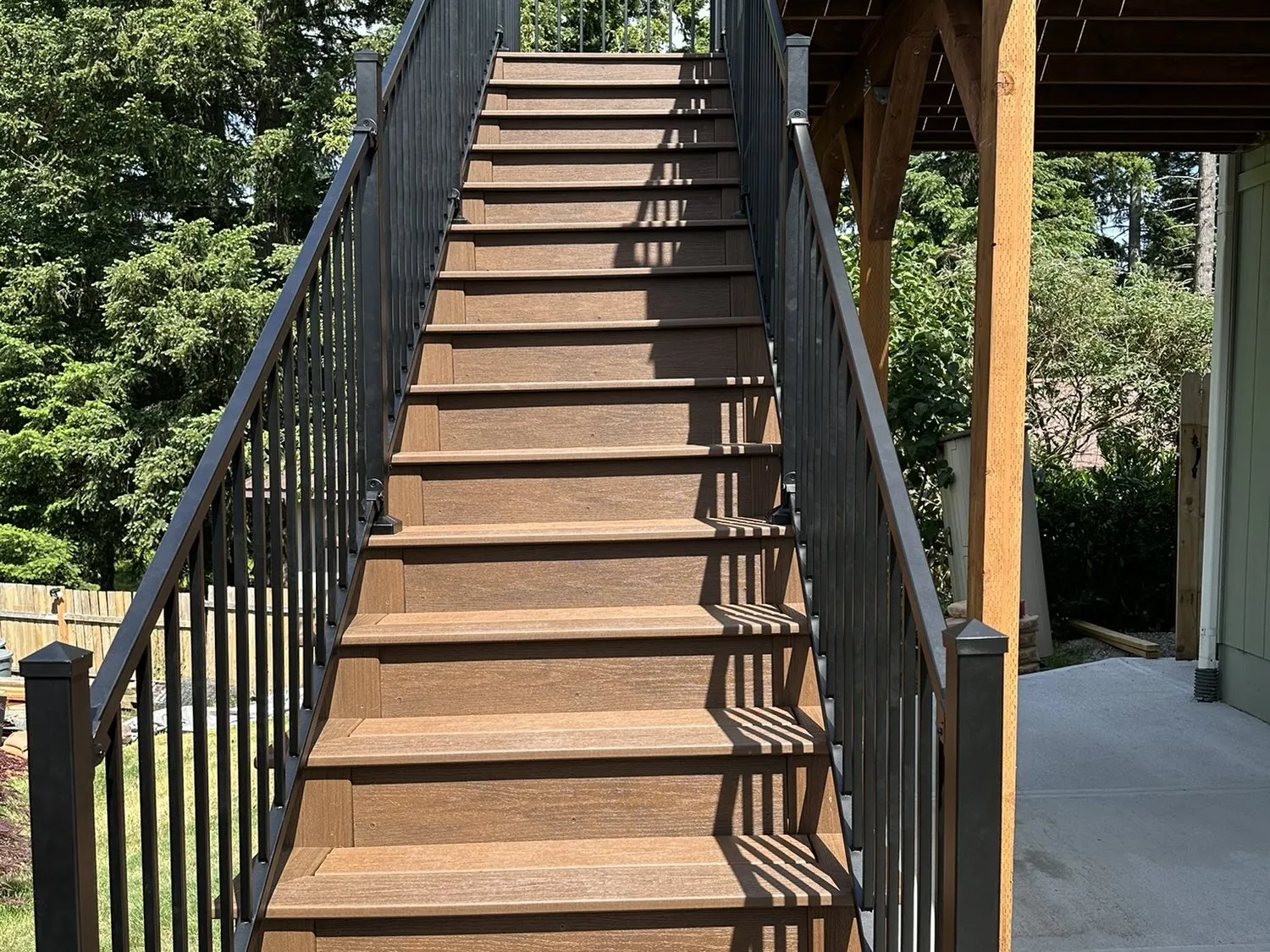 A long run of deck stairs with timber treads and black metal balusters