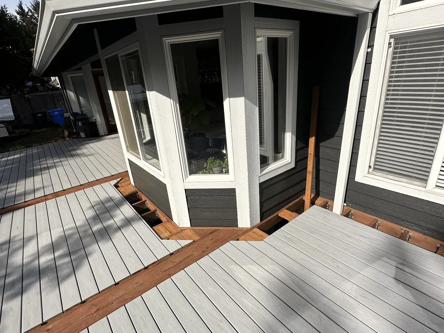 A bay window bump-out with new white windows and gray siding installed by All Home HX