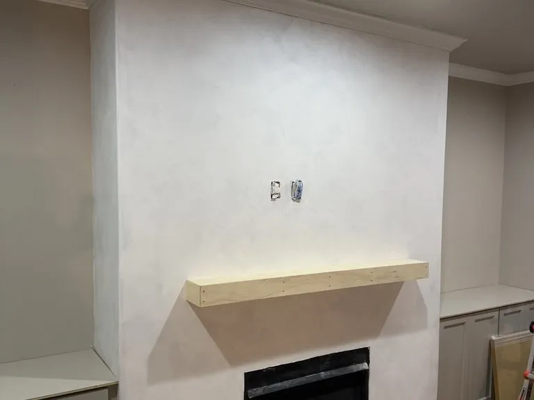 A finished fireplace wall with a plain timber mantel