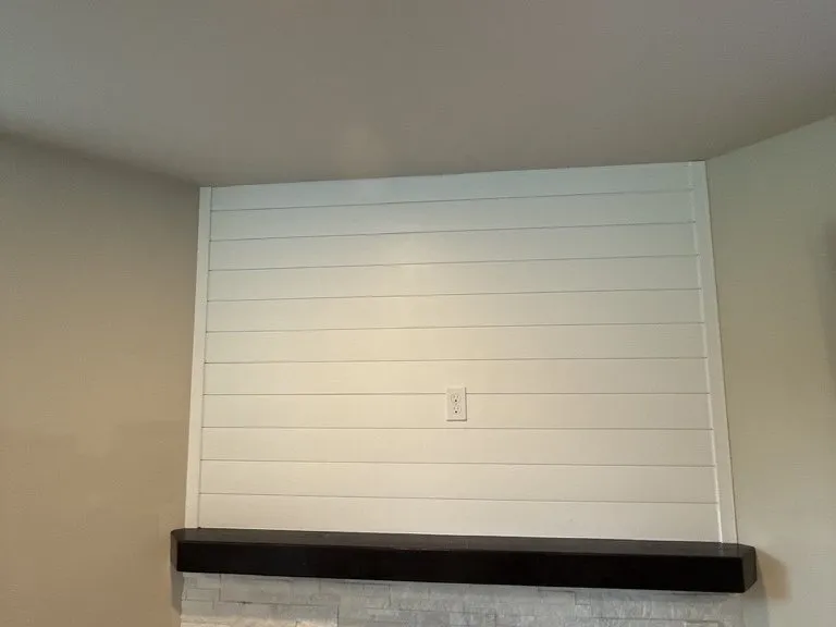 The finished shiplap wall and floating mantel, lit from above