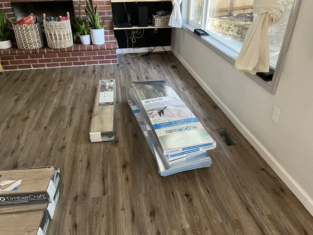 Boxes of plank on a part-finished floor beside a brick hearth