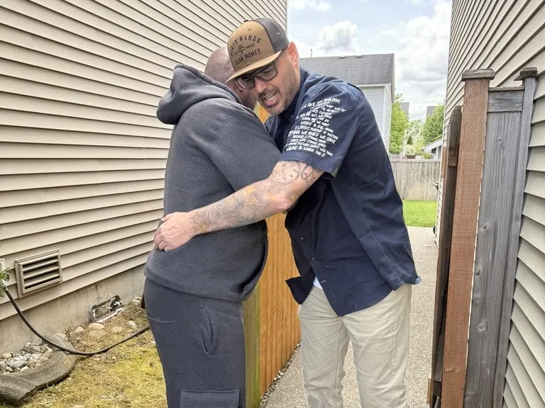 Two people sharing a hug beside the fence the crew had just put right