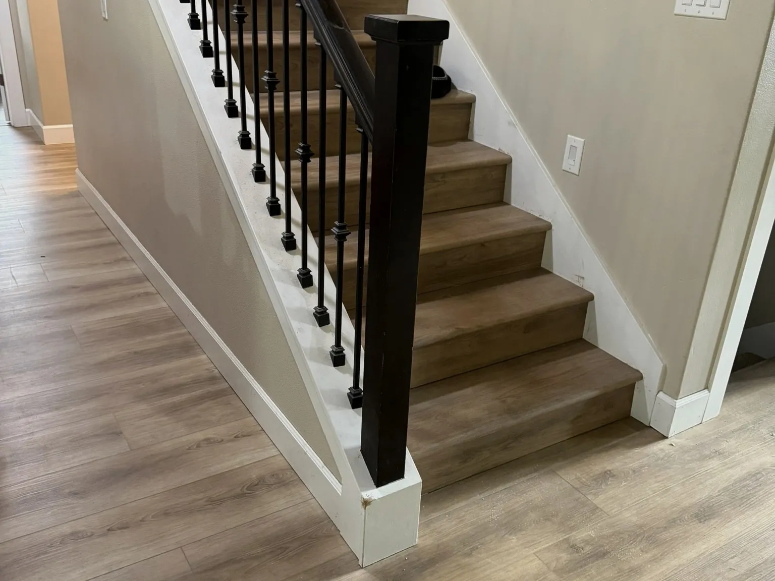 A finished staircase with light treads and black metal balusters