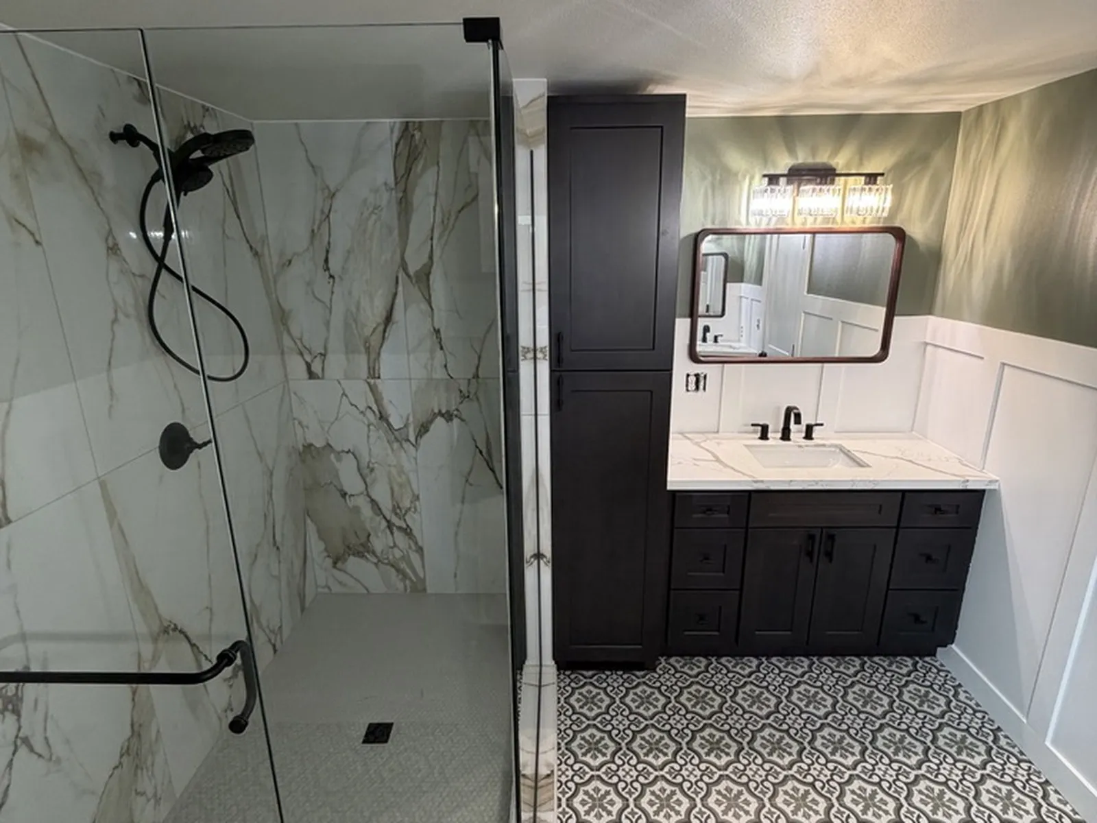 The finished main bathroom, with a marble-clad walk-in shower, a dark vanity and patterned floor tile