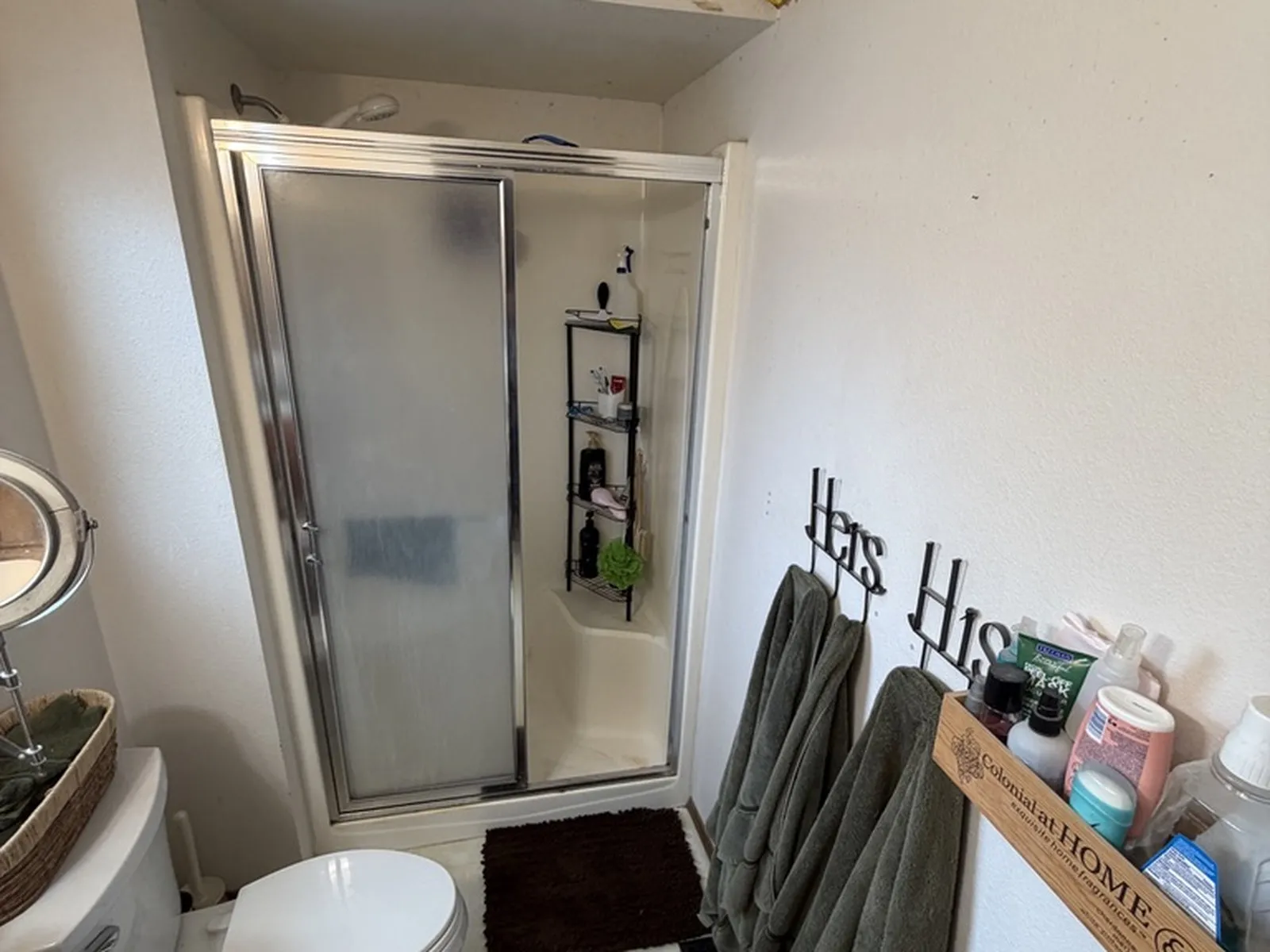 The main bathroom before work began, with a framed glass shower enclosure and a wallpaper border