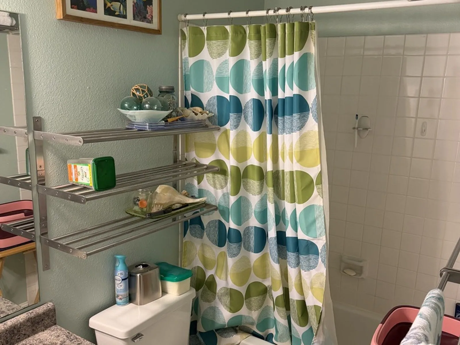 The hall bathroom before work began, with a tiled tub surround, a shower curtain and green walls