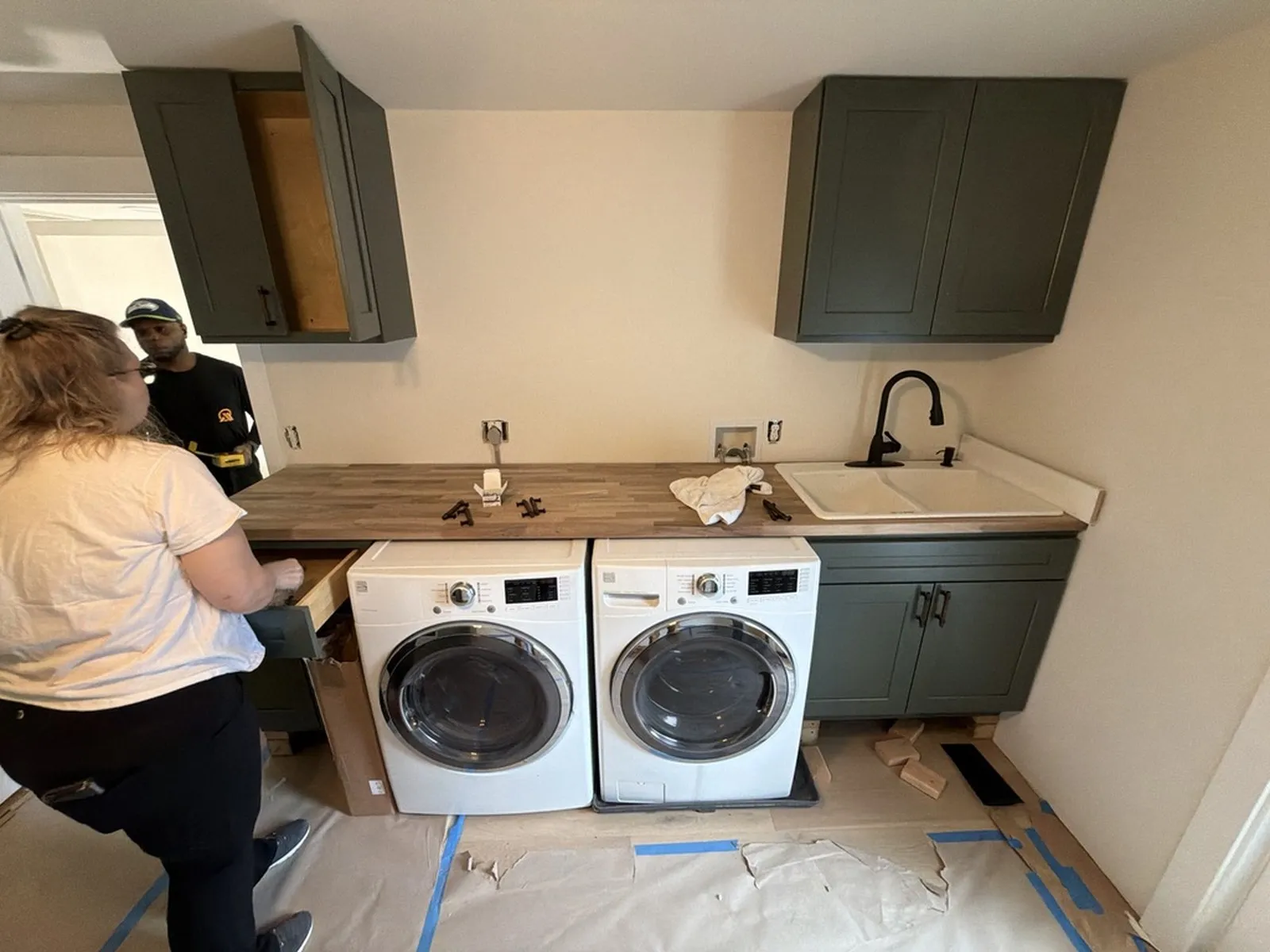 An All Home HX crew member fitting the new laundry room, with green cabinets and a butcher block counter