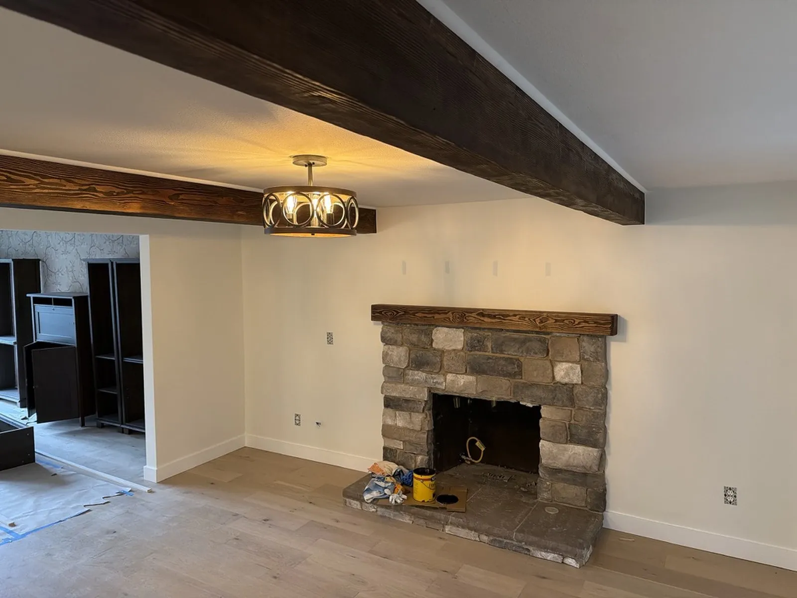 The finished living room, with a stone fireplace, a heavy timber mantel and an exposed beam across the ceiling