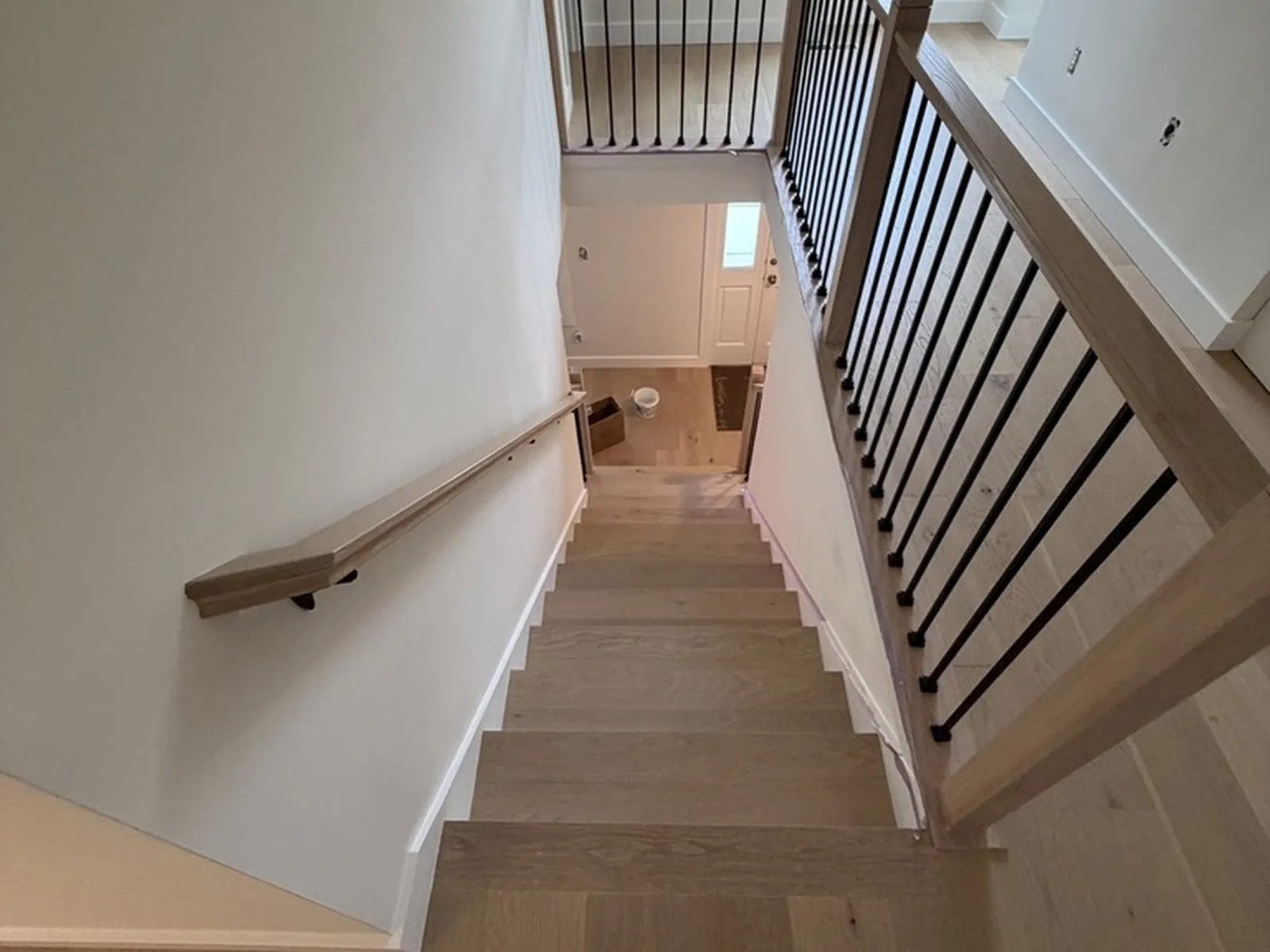 The finished stair looking down from the landing, showing the black balusters and oak handrail