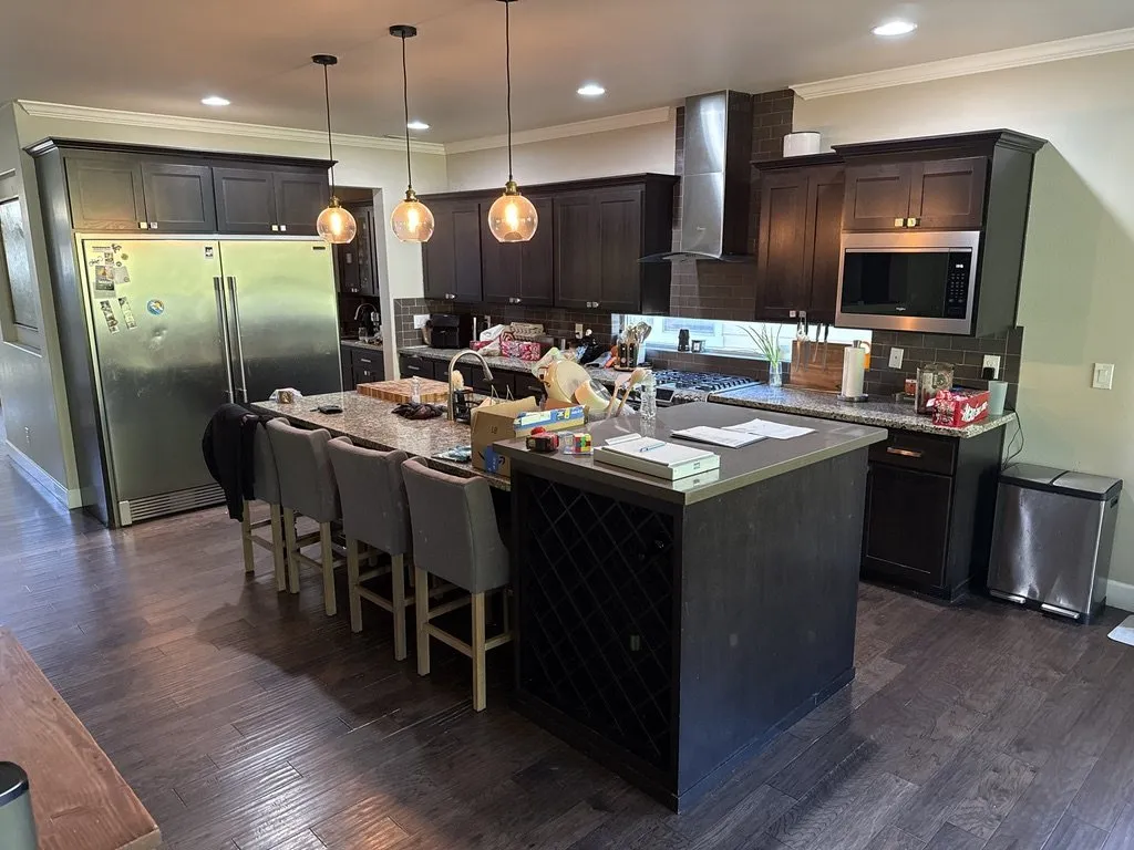 A dark-cabinet kitchen with a large island, bar seating and pendant lighting