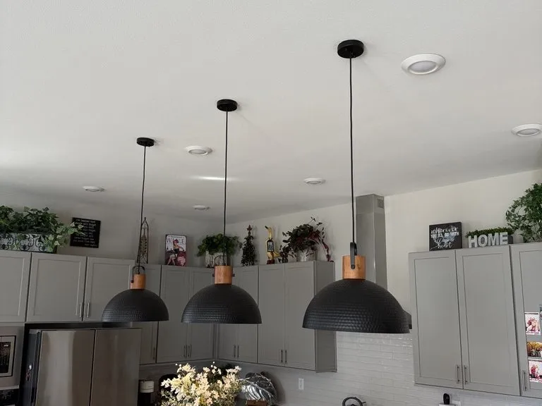 A finished kitchen with black dome pendants over the counter