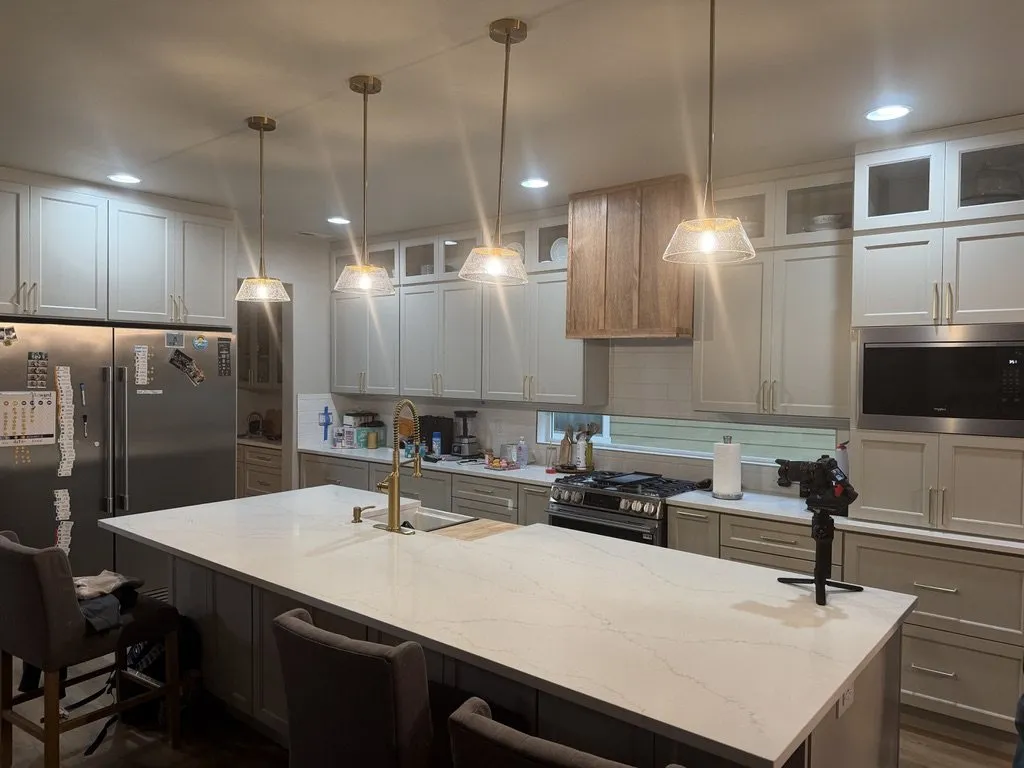 A white kitchen with an island, pendant lights and stainless appliances