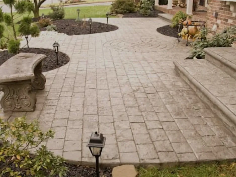 A paver patio with curved planting beds and low landscape lighting