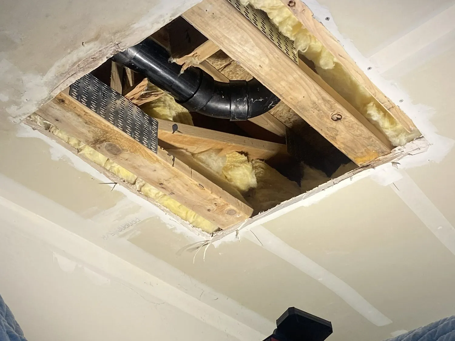 A ceiling opened up to expose ducting and joists during a repair